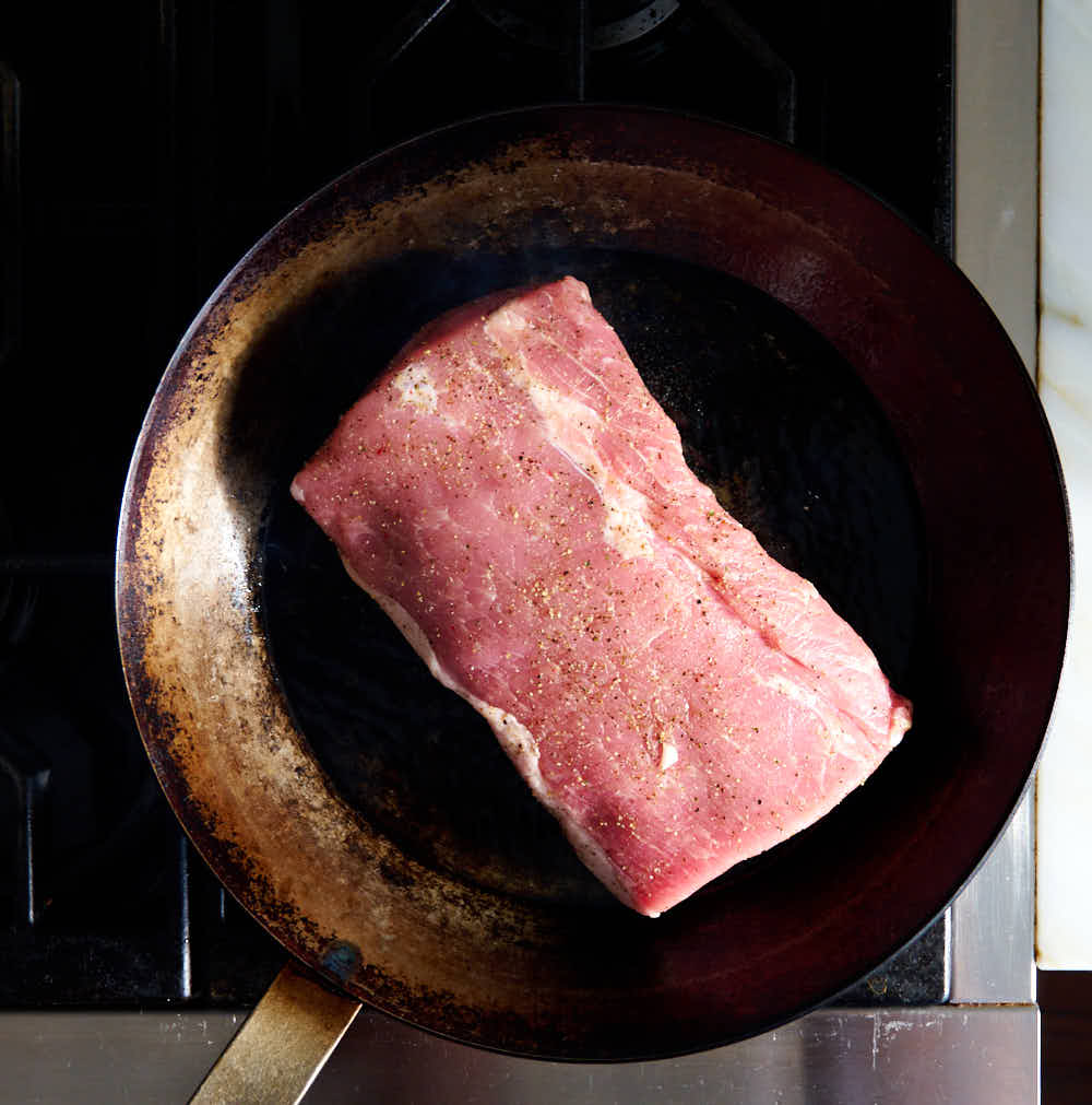 Searing pork loin roast on a skillet.