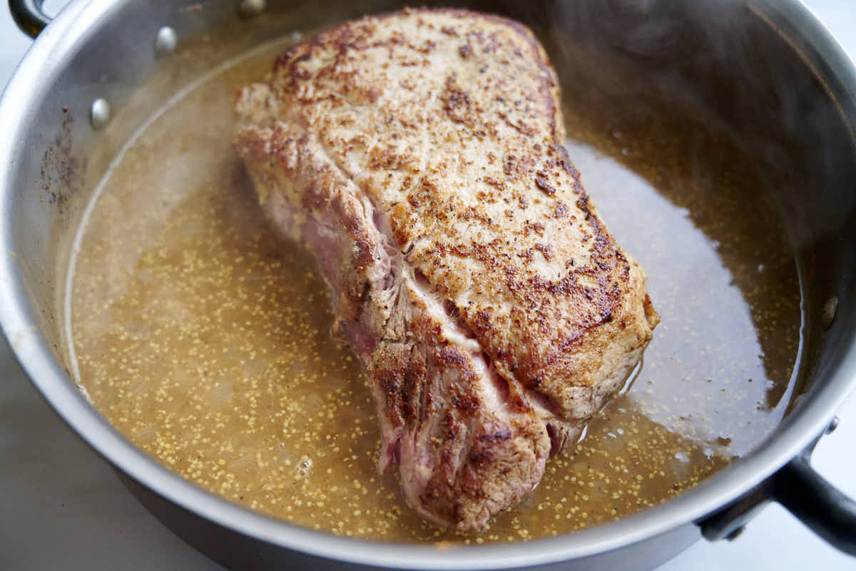 Cooking pork loin in white wine sauce over low heat.