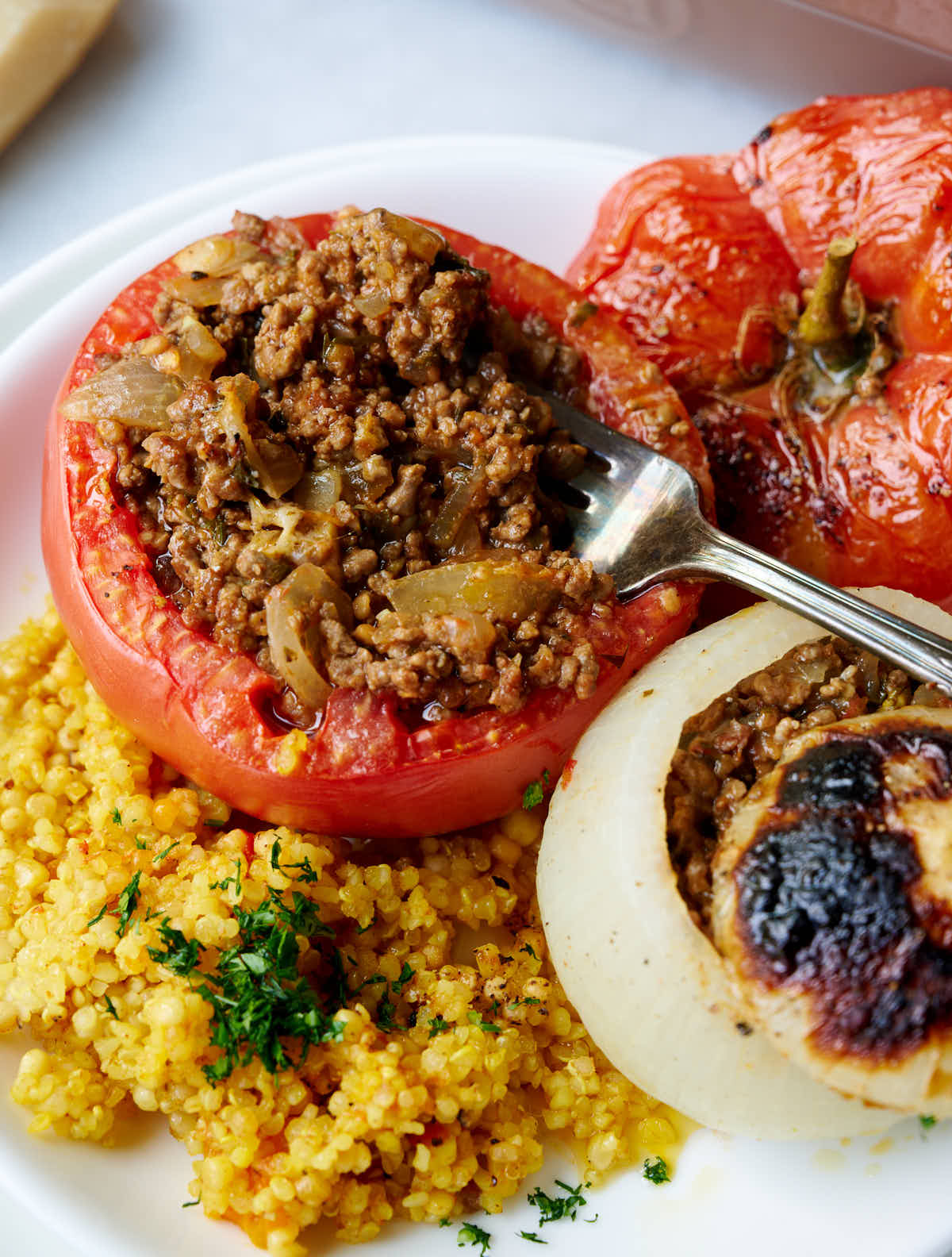 Baked tomatoes and onions stuffed with beef, chopped tomatoes, and onions, and baked with ancient grains. Insanely delicious and healthy.