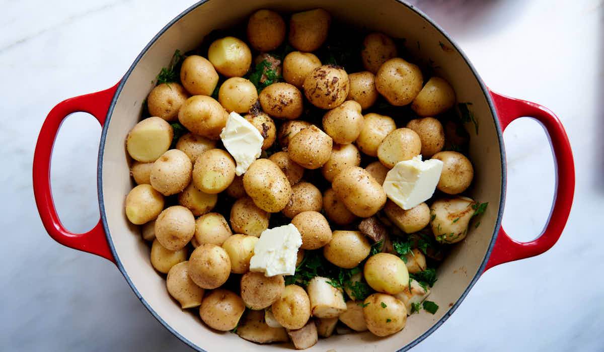 Potatoes with butter pats on top in a cast iron pot.